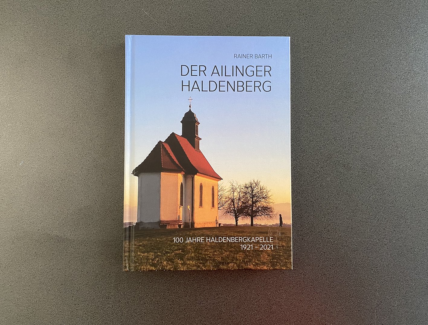 Buchcover zeigt eine Kapelle im Sonnenuntergang. Symbolbild für Buchherstellung